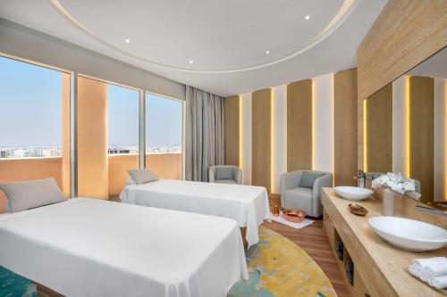 um quarto de hotel com 2 camas e uma secretária com um lavatório em Hilton Al Khobar King Fahd Causeway em Al Khobar
