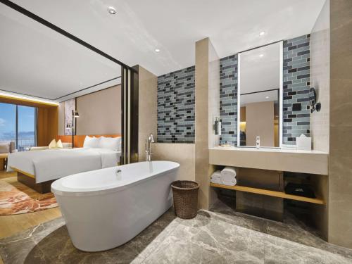 ein Badezimmer mit einer Badewanne und ein Schlafzimmer mit einem Bett in der Unterkunft Hilton Garden Inn Jinzhong Yuci in Jinzhong