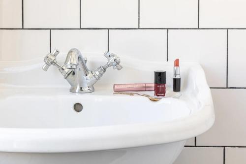Hôtel Basss في باريس: حوض الحمام مع أحمر الشفاه ومستحضرات التجميل عليه
