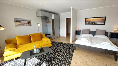 ein Wohnzimmer mit einer gelben Couch und einem Bett in der Unterkunft Villa Schwan by Rujana in Binz