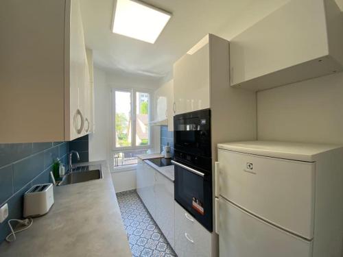 eine Küche mit einem weißen Kühlschrank und einer Spüle in der Unterkunft COROLLE Whole flat with garden near Paris in Vitry-sur-Seine