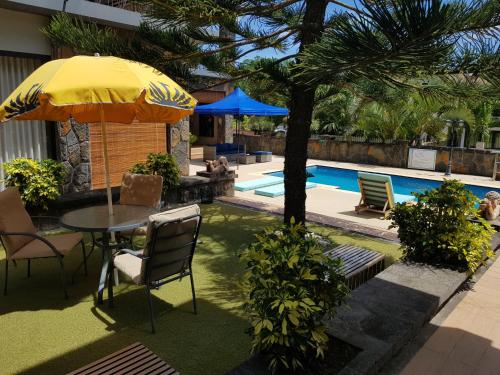 eine Terrasse mit einem Tisch und einem Sonnenschirm neben einem Pool in der Unterkunft Villas Rocher - Villa 3 in Grand Baie