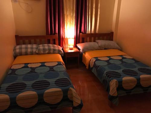 two beds in a small room with a window at TGH Guest House Badian in Badian
