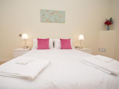 a large white bed with pink pillows and two lamps at 2 Bed in South Molton 62654 in Filleigh