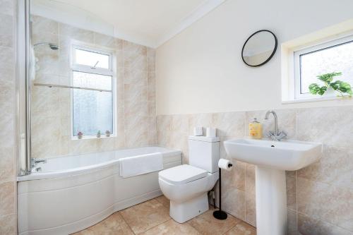 a bathroom with a sink and a toilet and a bath tub at Stylish House with Garden in Knottingly