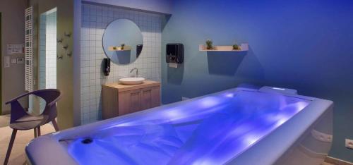 La salle de bains est pourvue d'une baignoire bleue et d'un lavabo. dans l'établissement DOMITYS L'AIGRETTE BLEUE, à Abbeville