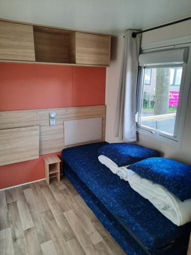 een kleine slaapkamer met een bed en een raam bij Chalet Trigano in Lauwersoog