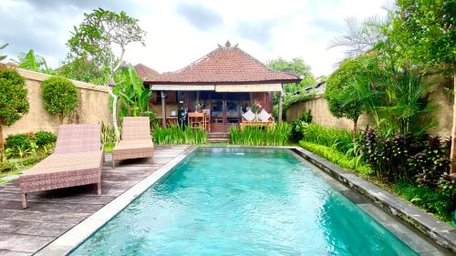 a swimming pool with two chairs and a house at NILUH Private Villas Ubud in Ubud