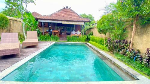 a swimming pool with two chairs and a house at NILUH Private Villas Ubud in Ubud