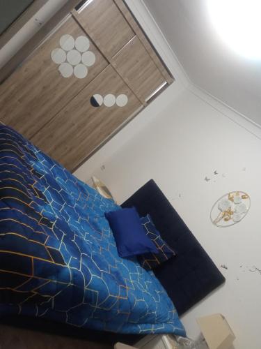 Schlafzimmer mit einem Bett mit blauer Bettwäsche und einem Fenster in der Unterkunft Appartement pré du stade olympique belgaid in Canastel