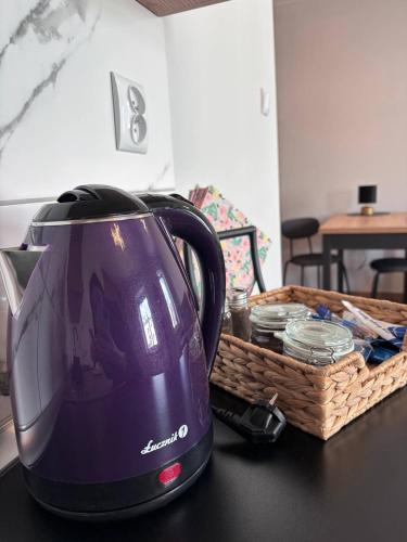 a purple tea kettle and a basket on a table at Kawalerka w centrum 42 in Łódź