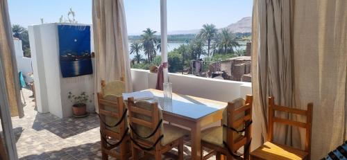 Una mesa y sillas en un balcón con vista al agua. en Abo Hisham Nile Flat, en Luxor
