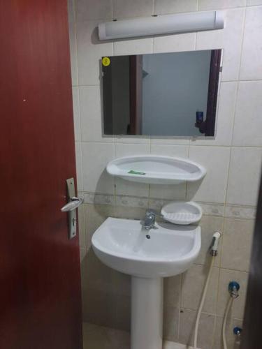 La salle de bains est pourvue d'un lavabo blanc et d'un miroir. dans l'établissement Furnished Studio for Rent, à Charjah