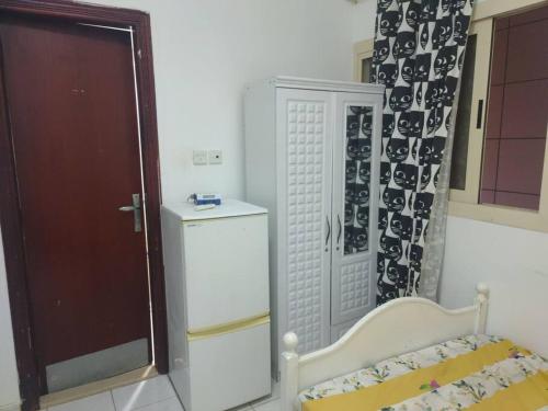 Cette chambre comprend un lit, un réfrigérateur et une fenêtre. dans l'établissement Furnished Studio for Rent, à Charjah