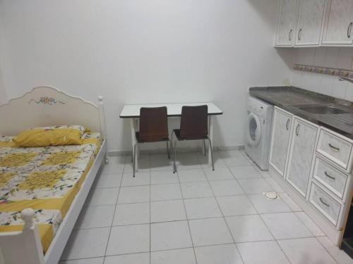 a kitchen with a bed and a table with chairs at Furnished Studio for Rent in Sharjah