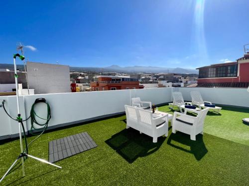 a balcony with white chairs and a table on the grass at La Cala de Alcalá Luxury in Alcalá