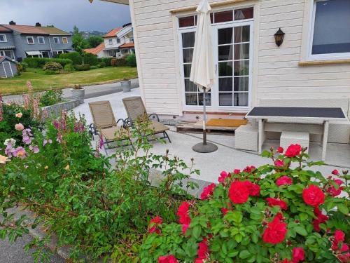 a patio with a table and chairs and flowers at Apartment Tryms vei 20a - Elegant eget bygg in Kristiansand