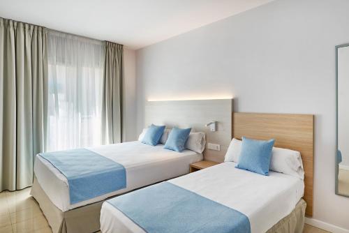 a hotel room with two beds and a window at URH Excelsior in Lloret de Mar