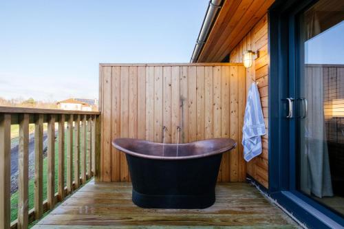 萊斯比的住宿－Laceby Manor - Spa & Golf Resort，浴缸位于围栏旁边的甲板上