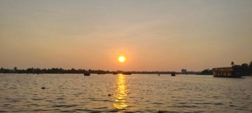 a sunset over a large body of water at Peace and love stay in Alleppey