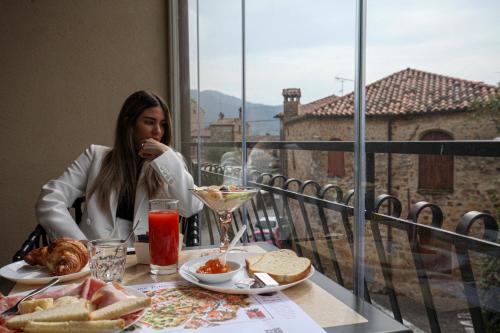 a woman sitting at a table with food on a balcony at La Giuggiola in Arqua Petrarca