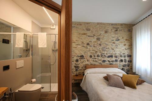 a bedroom with a bed and a stone wall at La Giuggiola in Arquà Petrarca