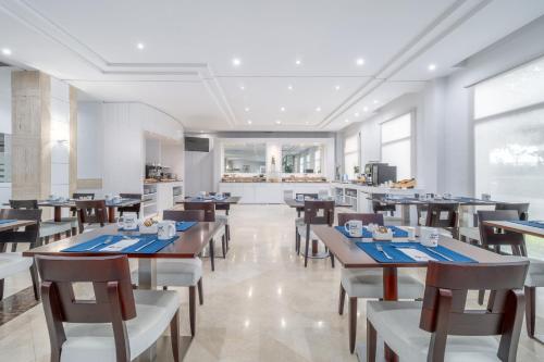 a restaurant with tables and chairs and a kitchen at Exe Pozuelo in Pozuelo de Alarcón