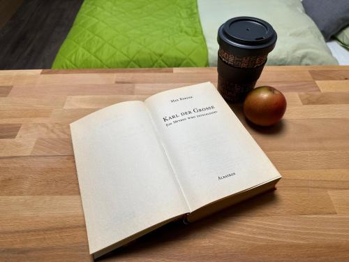 an open book on a table with an apple and a cup of coffee at Hotel Waldberg in Stolberg
