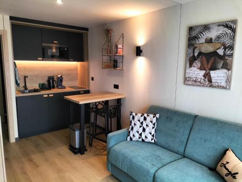 un salon avec un canapé bleu et une cuisine dans l'établissement Studio Zen et Bois, à Écouflant