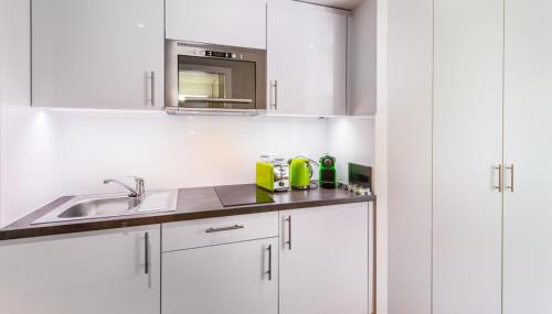 uma cozinha branca com um lavatório e um micro-ondas em N20 Residence by Homenhancement em Genebra