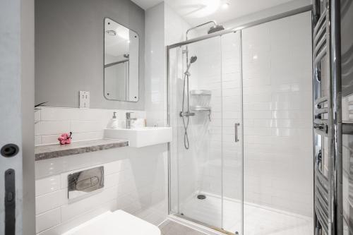 a white bathroom with a shower and a sink at GuestReady - Modern stay near World Museum in Liverpool