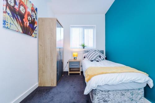a bedroom with a bed with a blue wall at GuestReady - Anfield Urban Escape in Liverpool