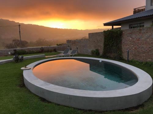 a large swimming pool in a yard with two chairs at Christiana Lodge in Plettenberg Bay