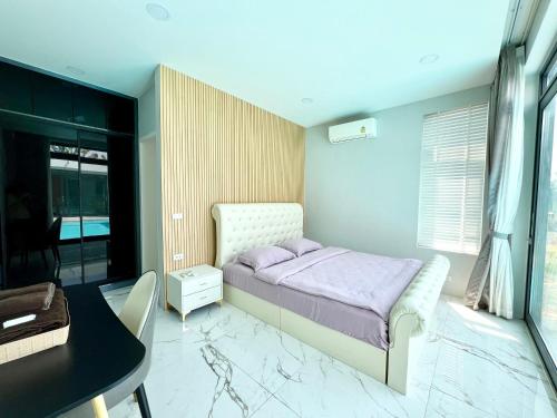 1 dormitorio con cama, escritorio y mesa en 芭提雅湖景泳池别墅2, en Nong Prue