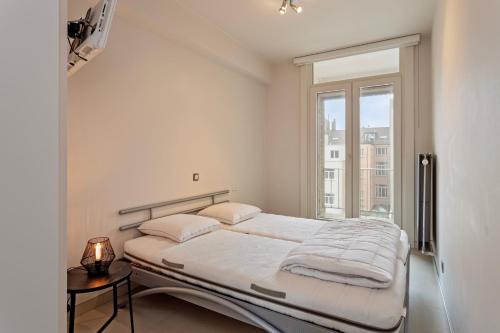 Habitación blanca con cama y ventana en Magdalena 5a 5ev, en Ostende