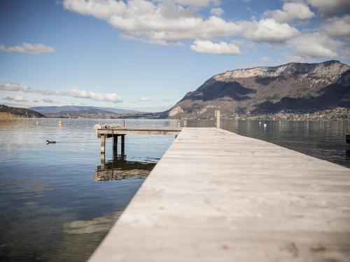 un quai sur un lac avec des montagnes en arrière-plan dans l'établissement Venez Chez Vous Les Pieds dans l'Eau, à Sévrier