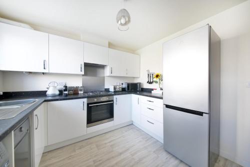 eine weiße Küche mit weißen Schränken und einem Kühlschrank in der Unterkunft GuestReady - Humble Abode by Anfield Stadium in Liverpool