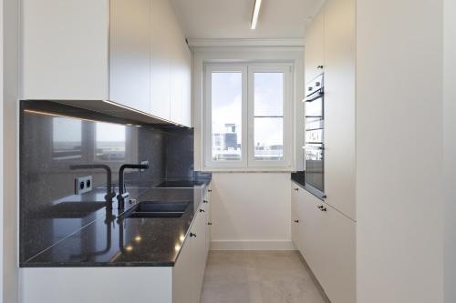 a white kitchen with a sink and a window at Zeebries 0505 e5 in Wenduine