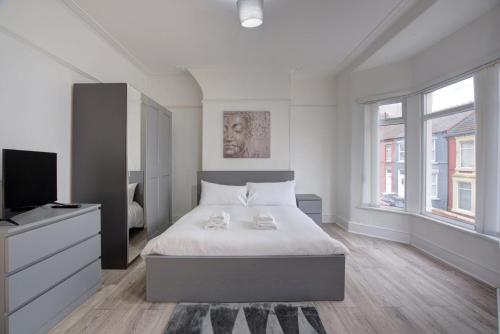 a white bedroom with a bed and a television at GuestReady - A monochrome home in Anfield in Liverpool