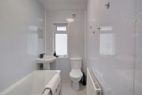 a white bathroom with a tub and a toilet and a sink at GuestReady - A monochrome home in Anfield in Liverpool