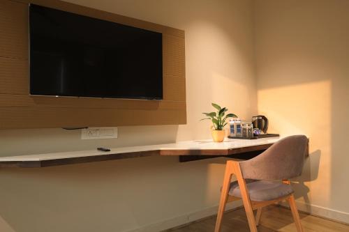 a room with a tv on a wall with a chair at Aurum Keys By VYDA in Bengaluru