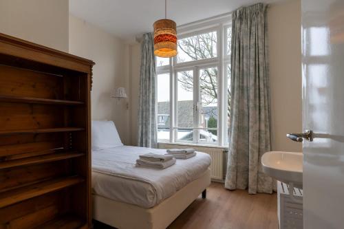 1 dormitorio con cama, ventana y lavamanos en NEW Hello Zeeland - Vakantiehuis Markt 10 en Domburg