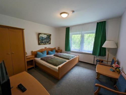 een slaapkamer met een bed, een bureau en een raam bij Haus Am Waldesrand in Herzberg am Harz