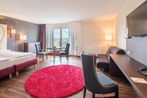 a hotel room with a bed and a red rug at Airways Hotels Frankfurt Airport West in Raunheim