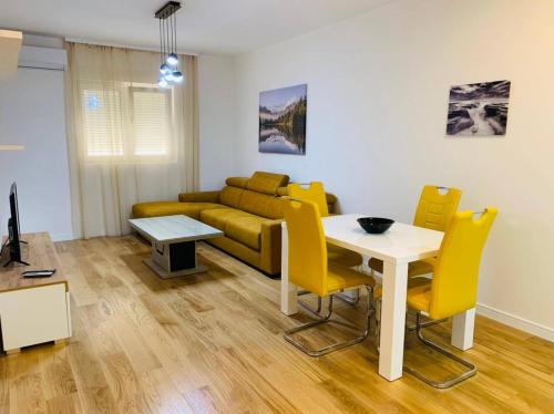 sala de estar con sofá, mesa y sillas amarillas en квартира у моря Зетаградня ул Барских логораша, en Bar