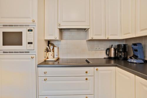 a white kitchen with white cabinets and a microwave at Kievit 0302 B3 3ev in Wenduine