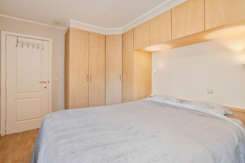 a bedroom with a white bed and wooden cabinets at Kievit 0302 B3 3ev in Wenduine