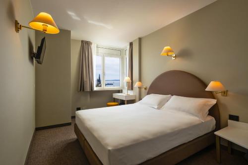 Un dormitorio con una gran cama blanca y una ventana en Hotel Nettuno, en Bardolino