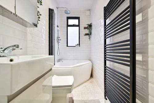 a white bathroom with a sink and a tub and a toilet at The Perfect Retreat-3 bedroom garden with Hot Tub in London