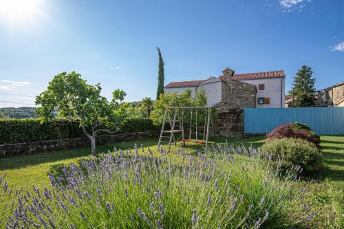 a garden with a swing and purple flowers at Rustic Villa Lavanda - Pool & Garden - Happy Rentals in Šmarje